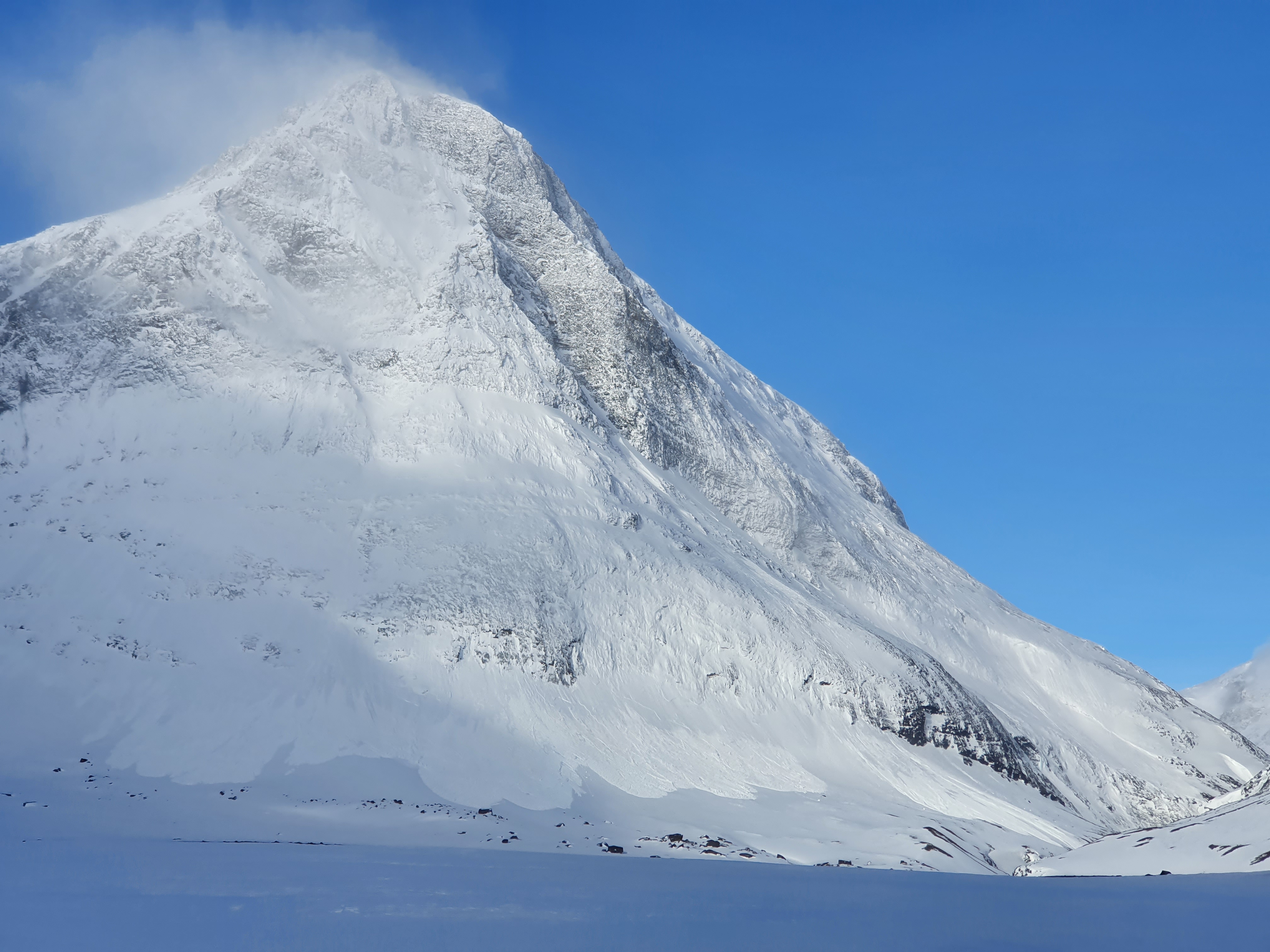 Snöklätt fjäll där man ser spår av en lavin som utlöst i form av snö som rasat ner.